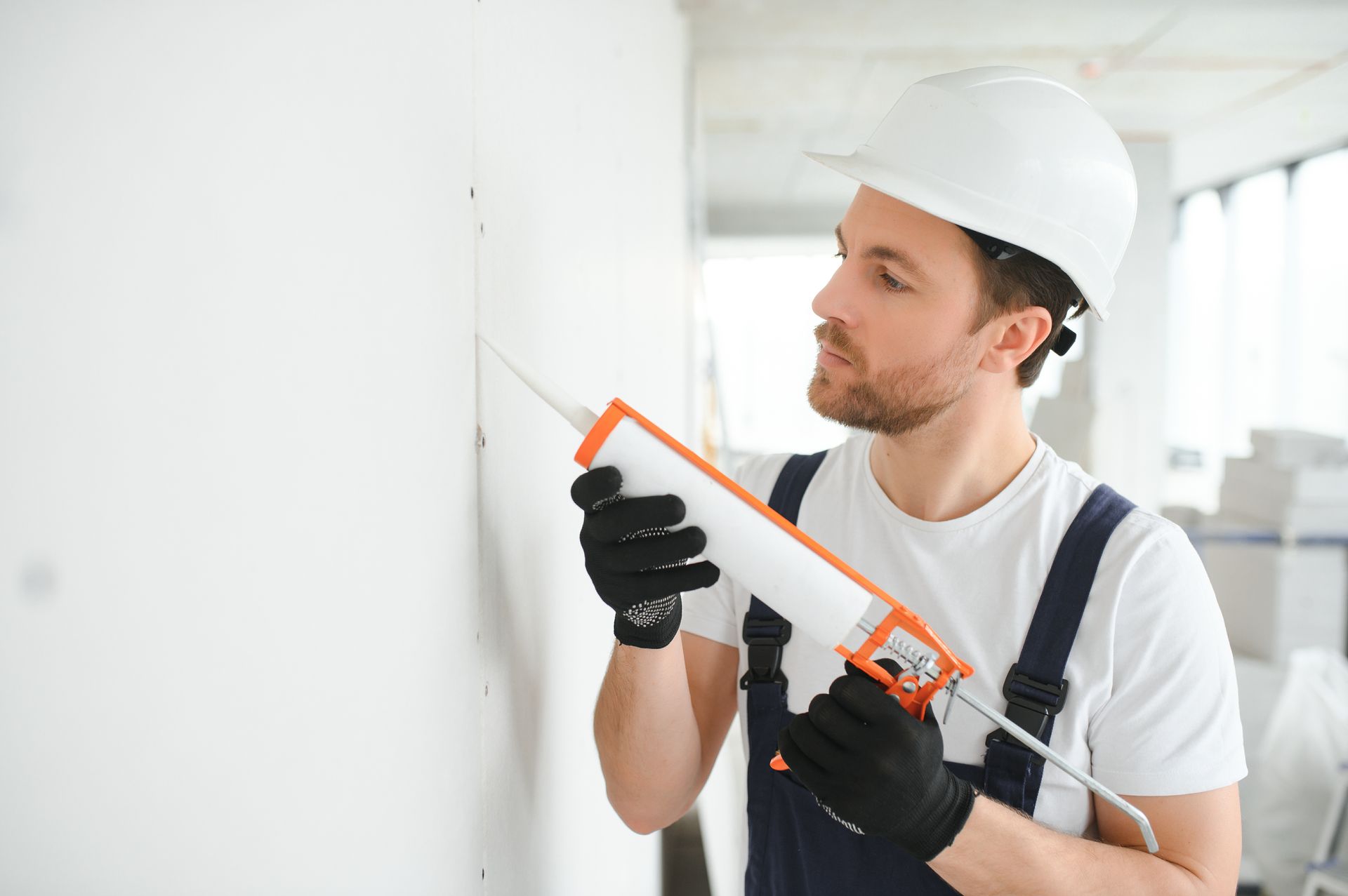 A man is applying caulk to a wall.