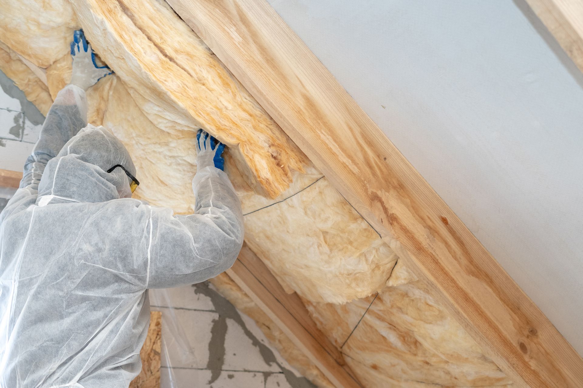 A man in a protective suit is insulating the roof of a house.