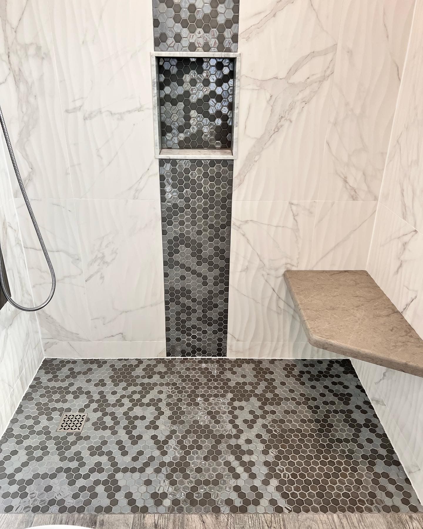 A bathroom with a walk in shower and a bench.