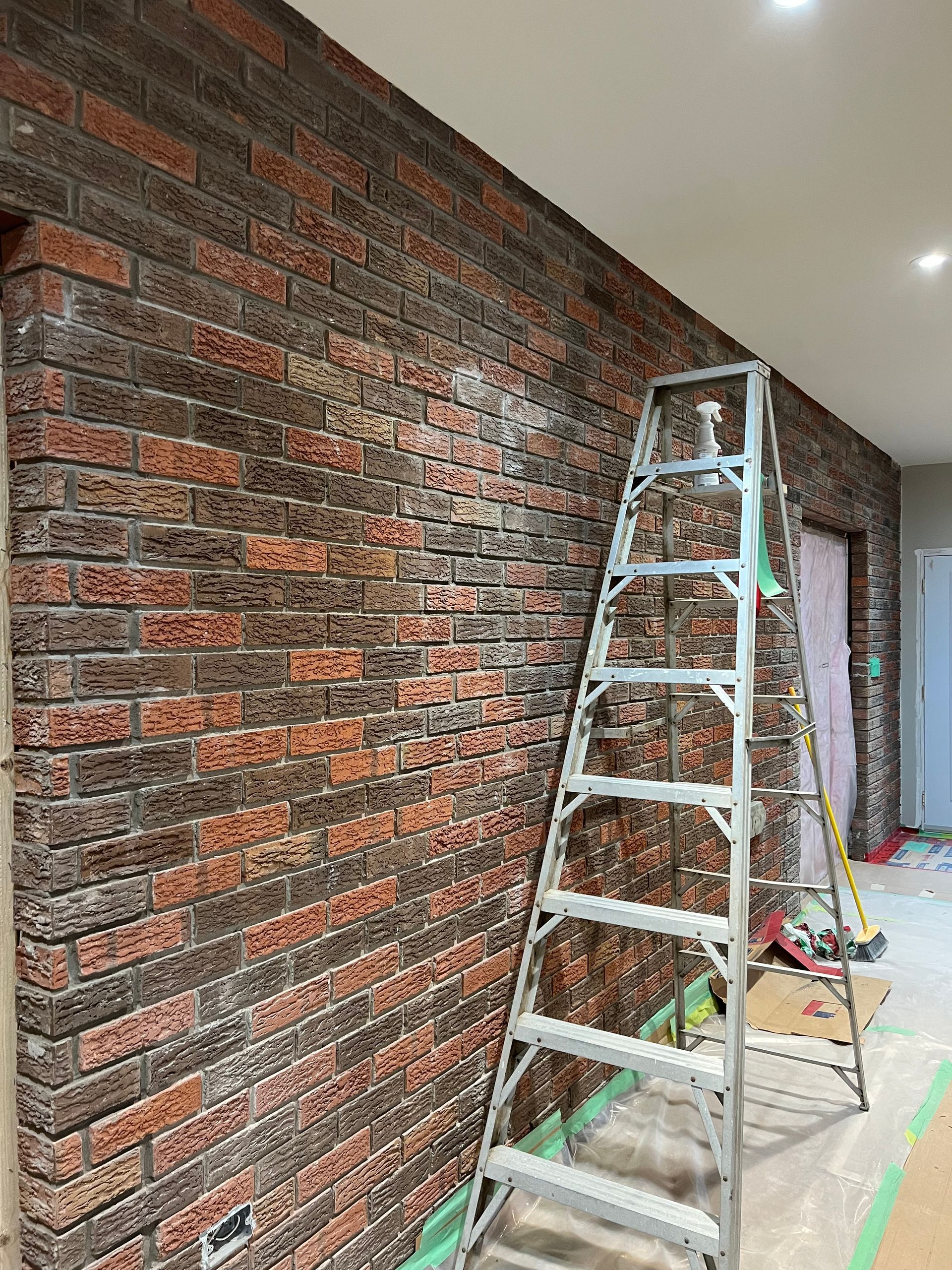 A ladder is sitting in front of a brick wall.