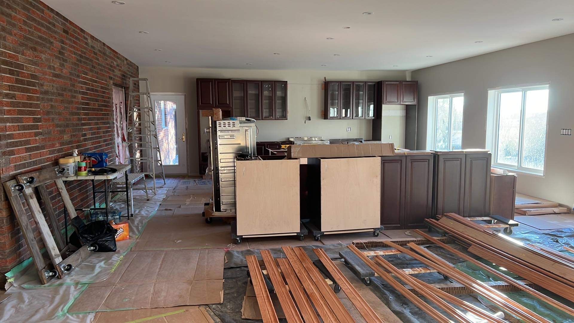 A kitchen is being built in a house with a brick wall.