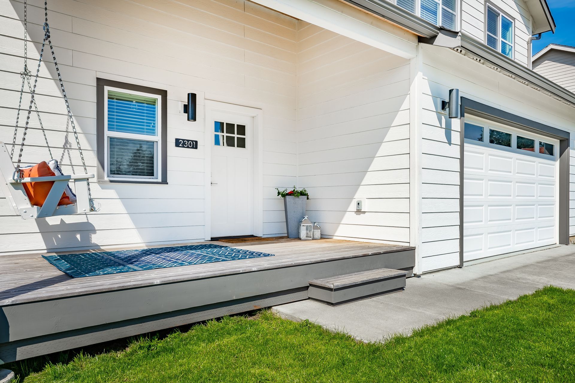 A white house with a white garage door and a porch.