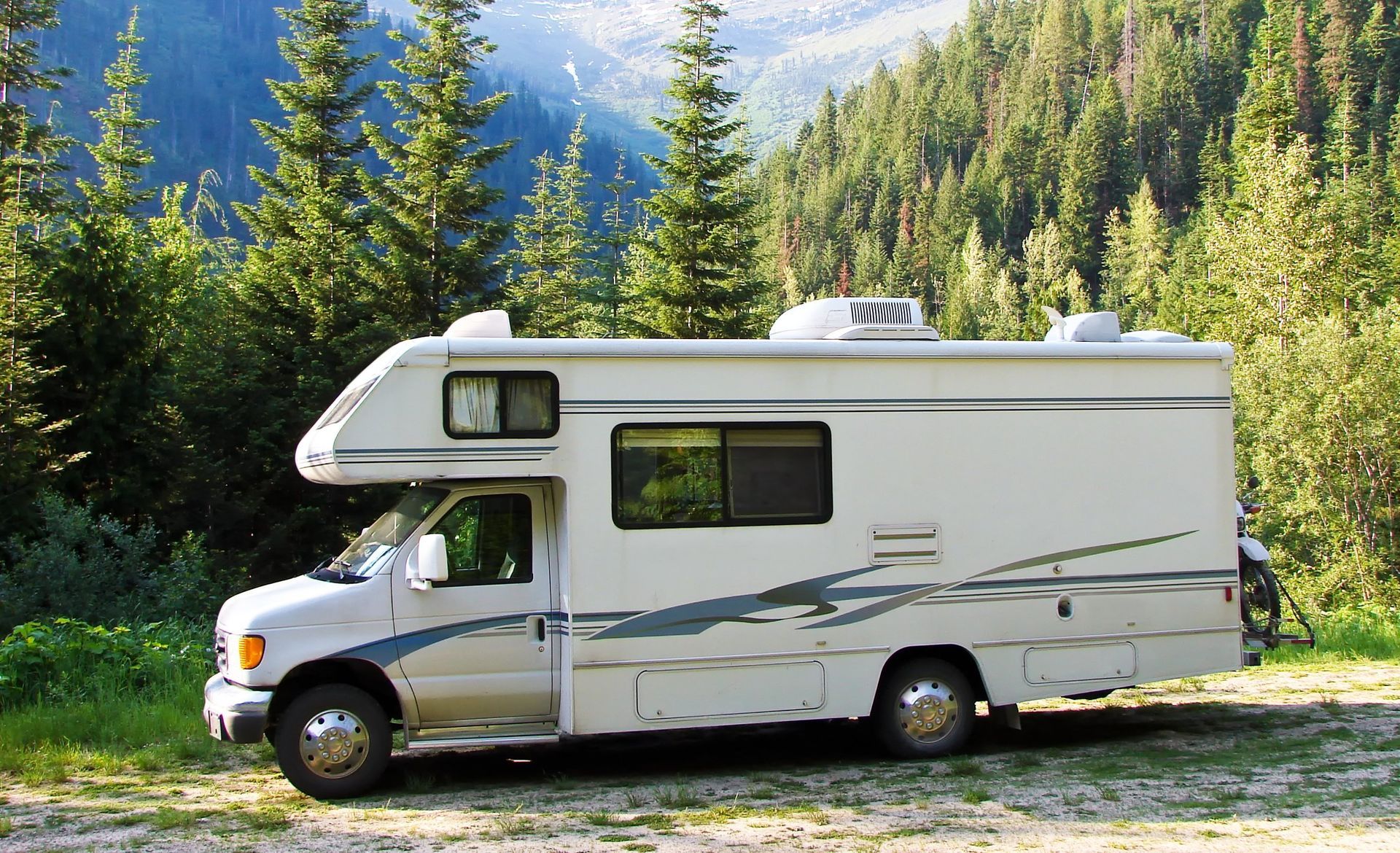 A white rv is parked in the middle of a forest