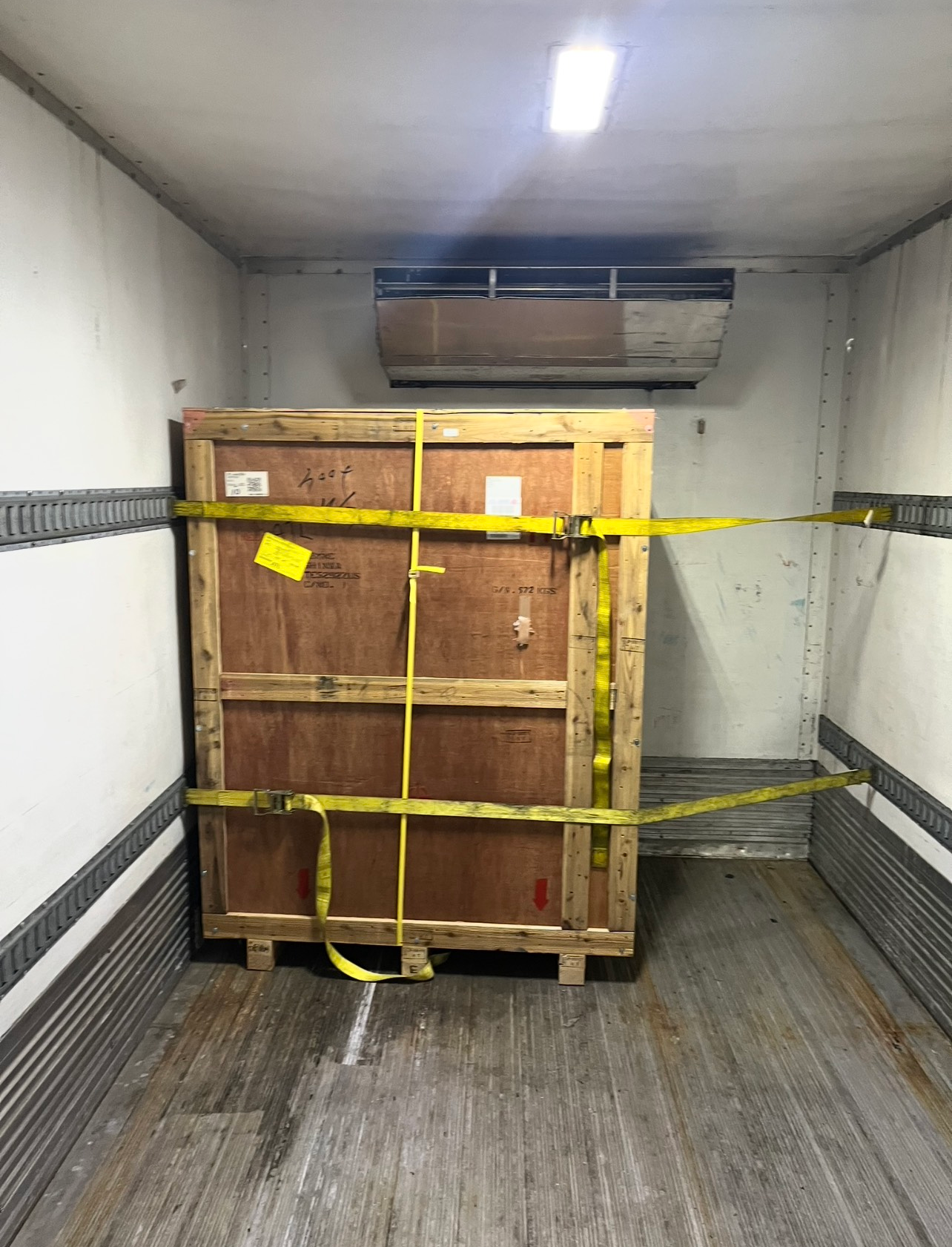 Open back of a refrigerated truck with pallets, goods, and lift gate.
