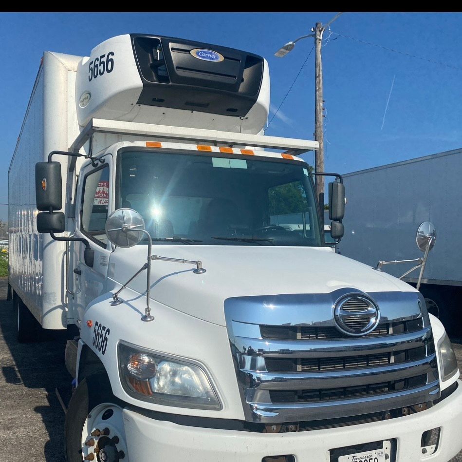 White refrigerated truck parked outdoors on a sunny day.