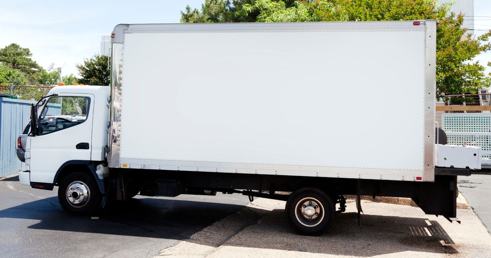 White box truck parked on a paved road, under a sunny sky.