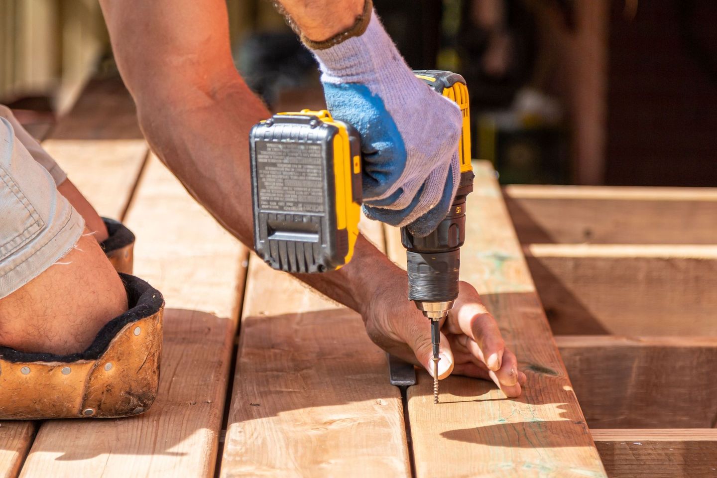 a man is using a drill on a wooden deck