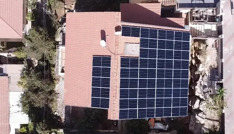 מבט מלמעלה על גג רעפים אדום עם פאנלים סולאריים מותקנים.