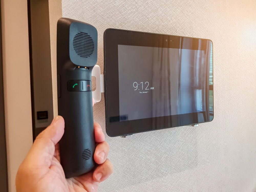 A Hand Holding a Black Phone Receiver Next to a Wall-mounted — Flexicoms Communications in Tully, QLD