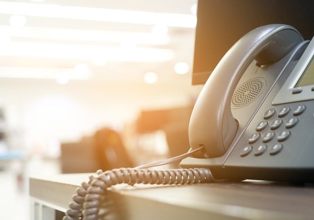A Black Office Phone on a Desk in a Bright Office Setting — Flexicoms Communications in Innisfail, QLD