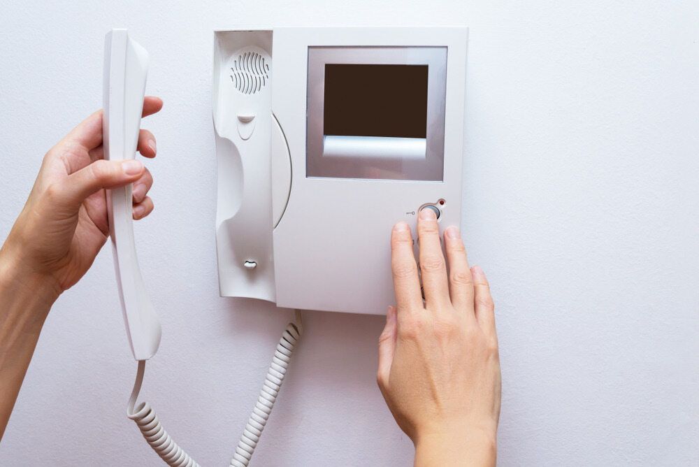 Hands Interacting With a White Intercom Device Mounted on a Wall — Flexicoms Communications in Innisfail, QLD
