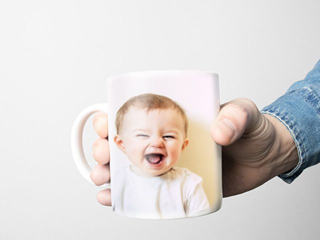 hand holding a mug with a picture of a baby on it