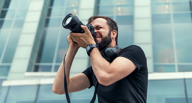 Man taking a picture with a camera next to a building