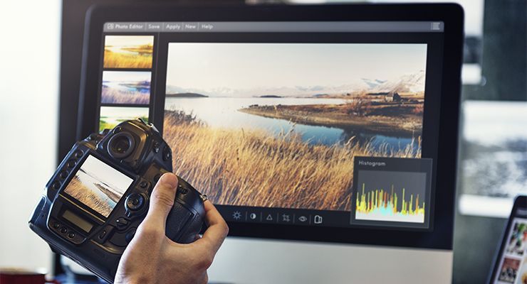 Hand holding a camera in front of computer screen