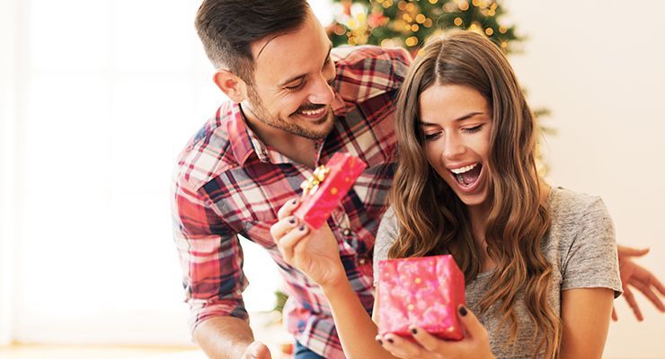 Woman opening a gift with husband behind her