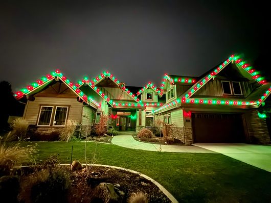 A large house is decorated with christmas lights at night.