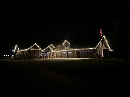 A large house is lit up at night with christmas lights.