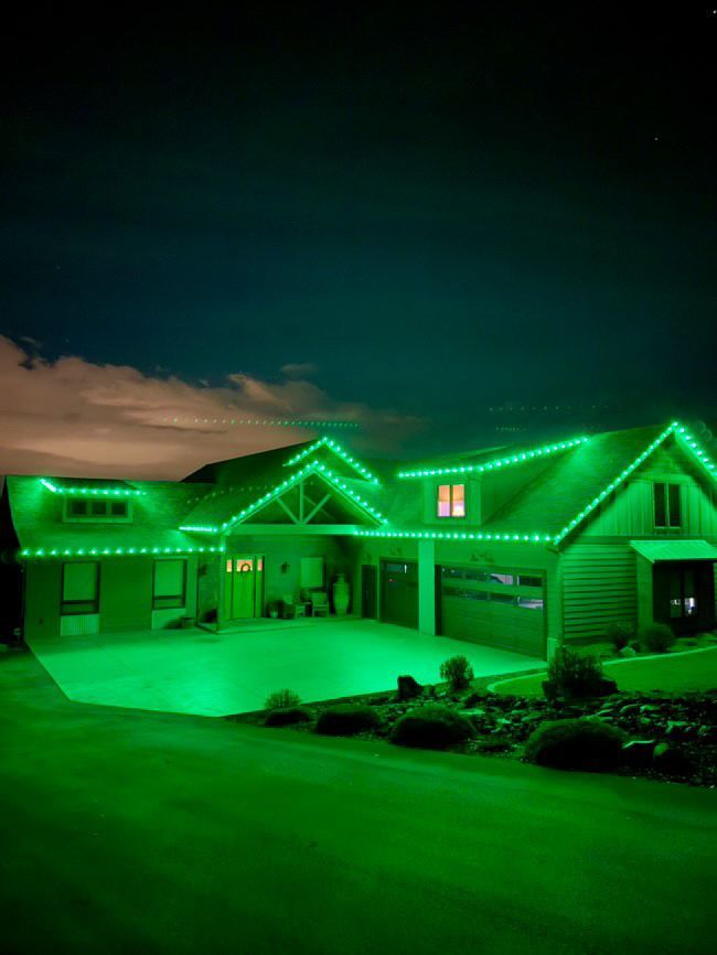 A house is lit up with green lights at night.