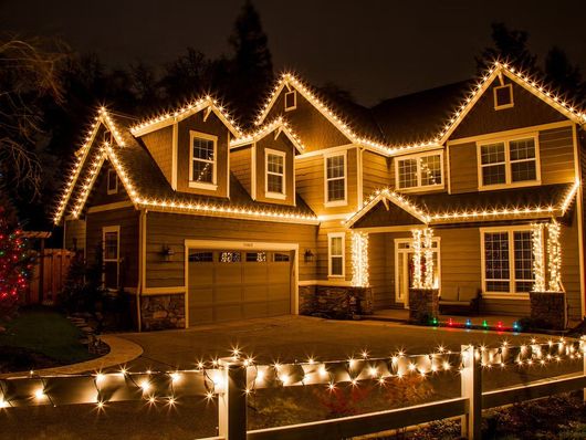 A large house is decorated with christmas lights at night.