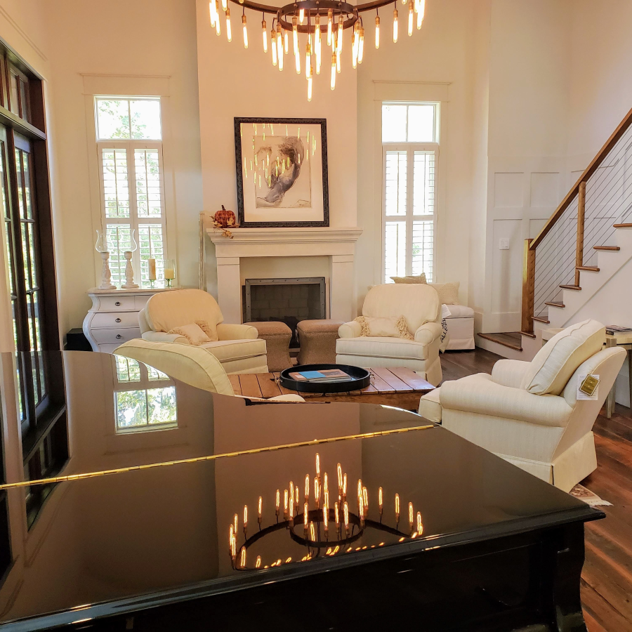 A living room with a piano and chairs and a fireplace