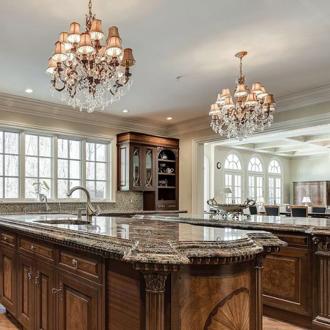 A kitchen with a large island and two chandeliers hanging from the ceiling