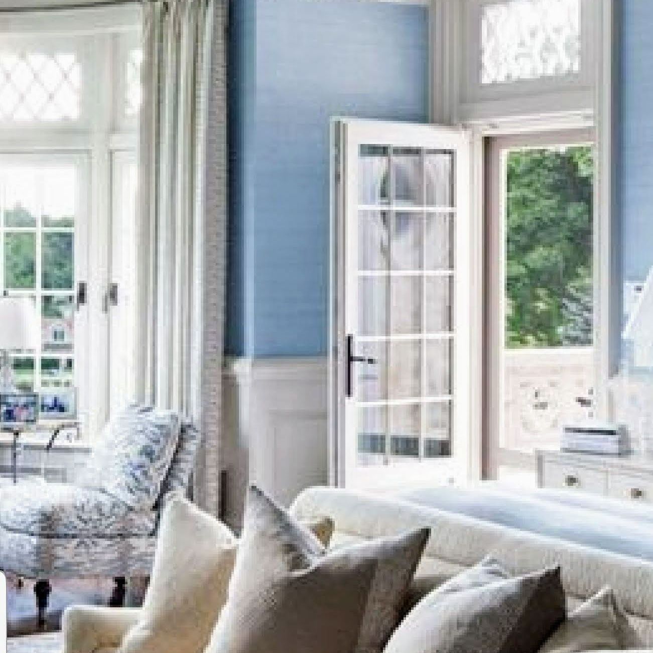 A living room with blue walls and white furniture and a couch.