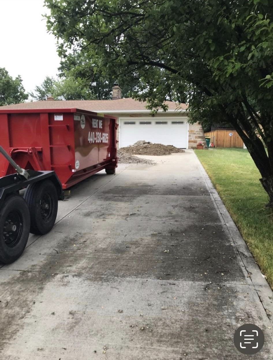a red dumpster is parked in the driveway of a house