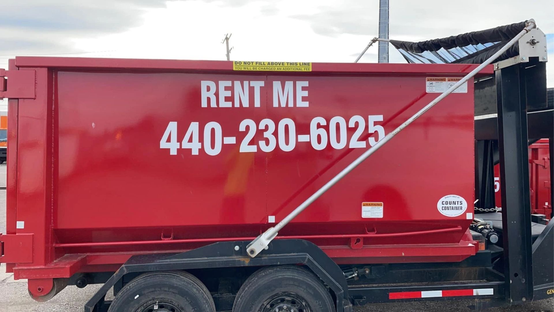 a red dumpster with the phone number 440-230-6025 on it