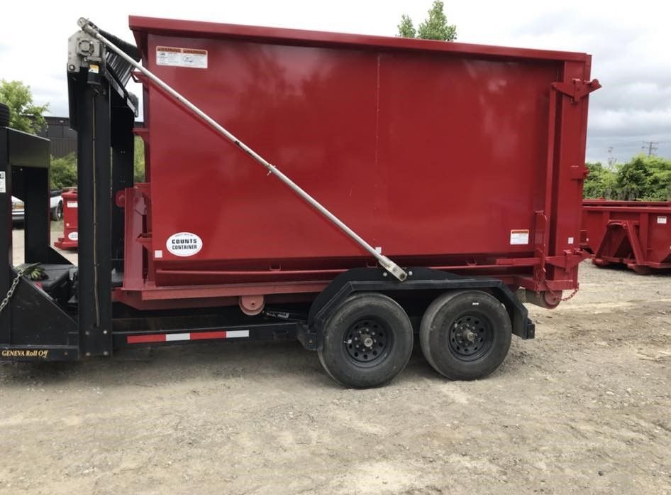 a red dumpster on a trailer with a crane attached to it