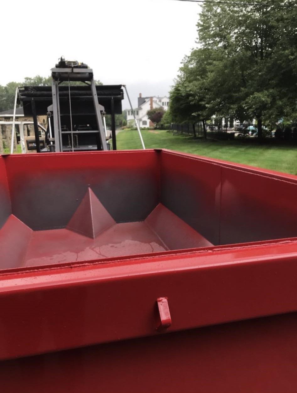 a red dumpster with a ladder in the background