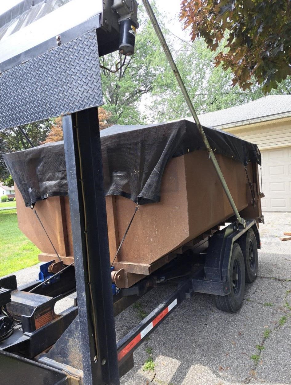 a dumpster on a trailer is being lifted by a crane