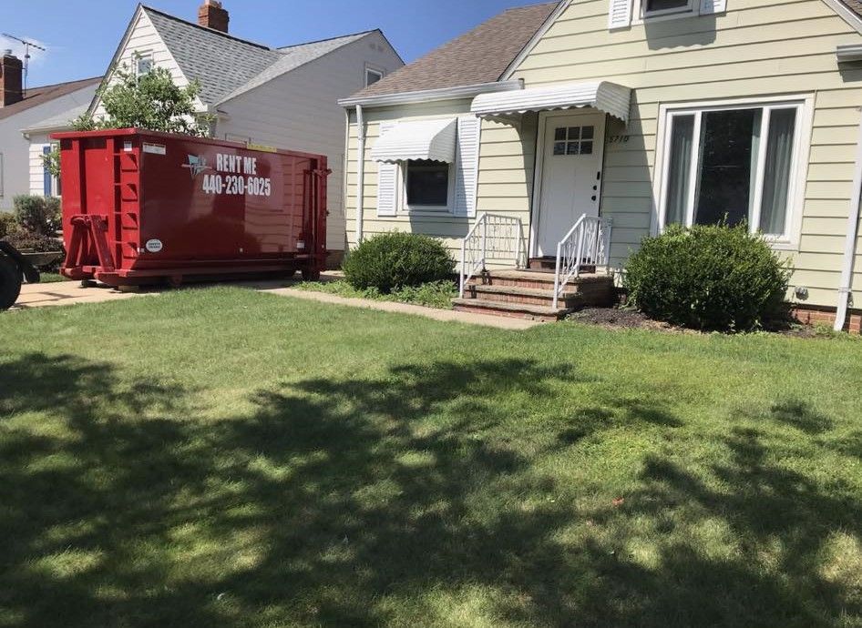 a red dumpster is parked in front of a house .