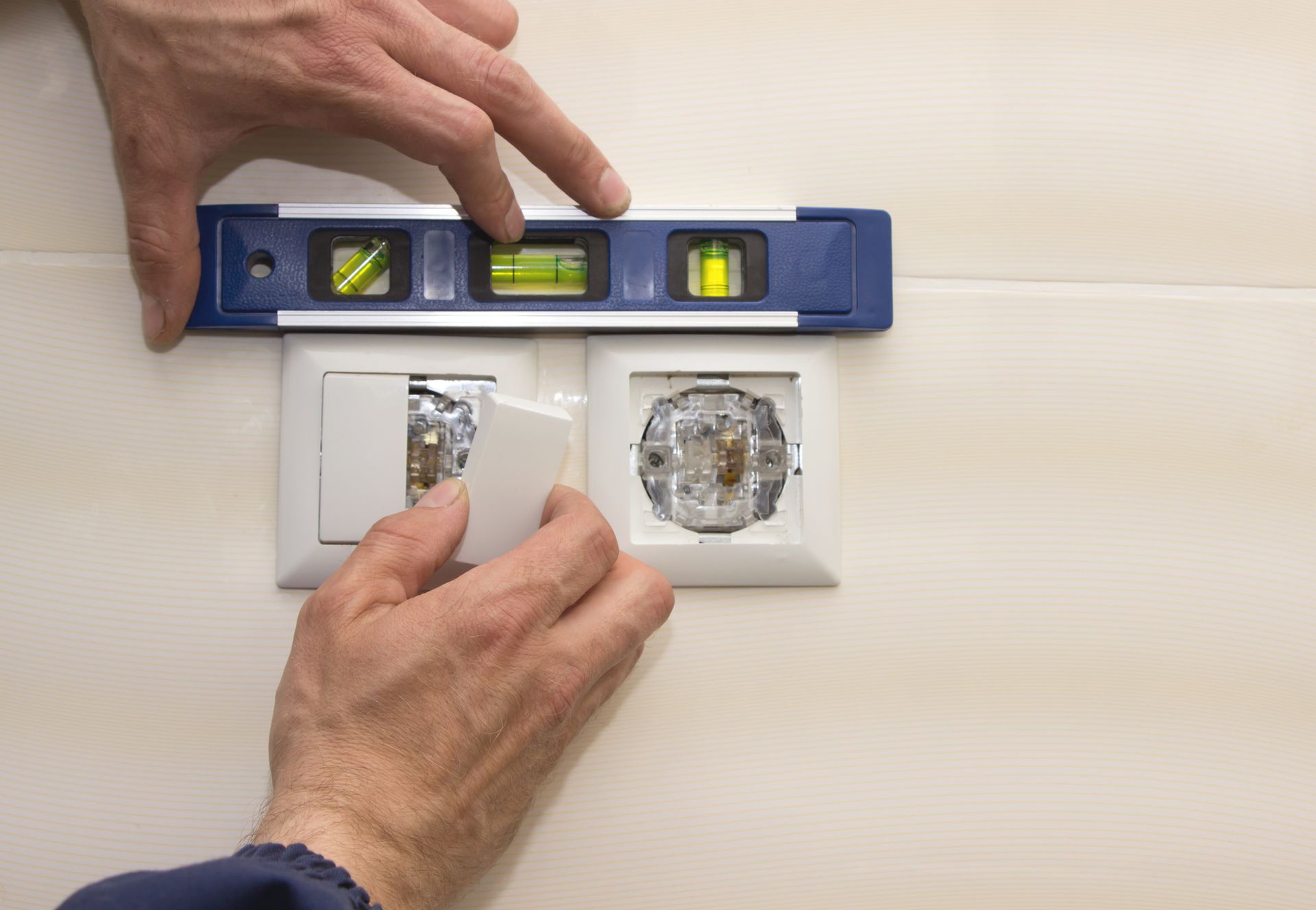 A person is measuring a light switch with a level.