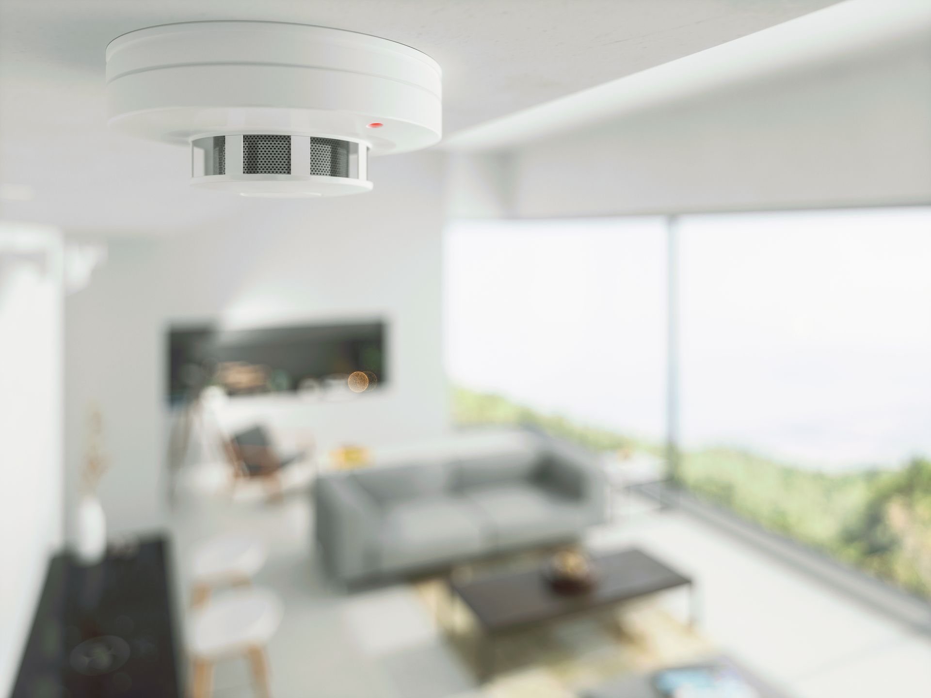 A smoke detector is mounted on the ceiling of a living room.