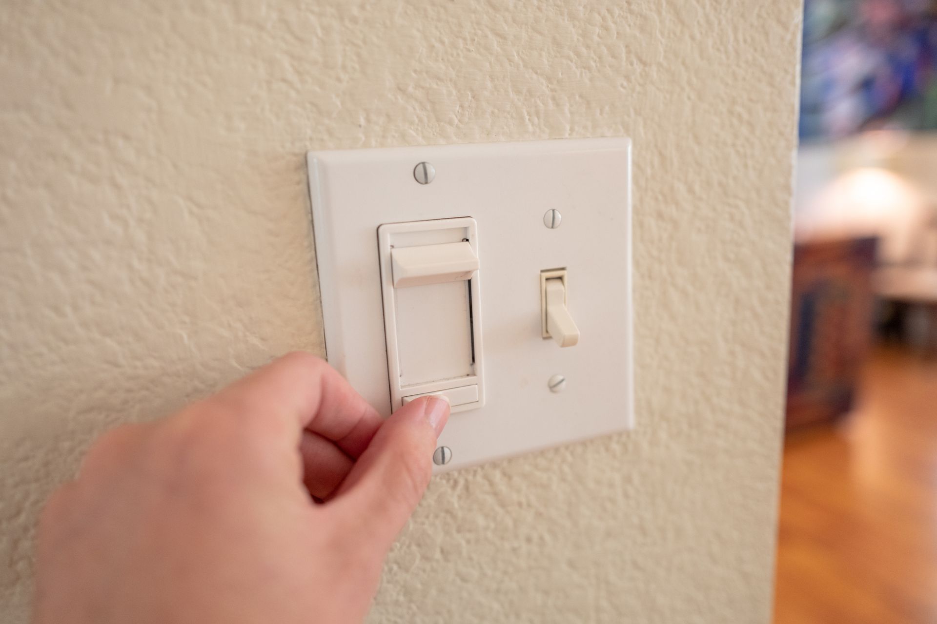 A person is turning a light switch on a wall.