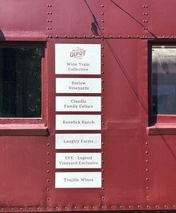 Sign on a red train car lists wine tasting venues: Wine Trails Collective, Barlow Vineyards, etc.