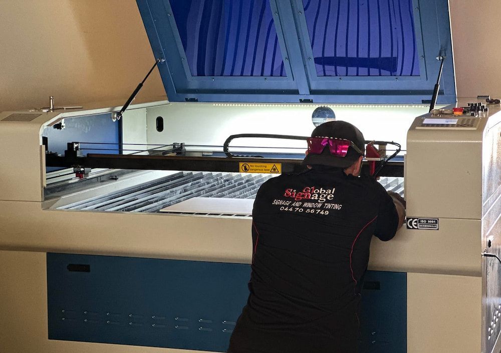 A Man Wearing Sunglasses is Working on a Machine — Global Signage In Ingham, QLD