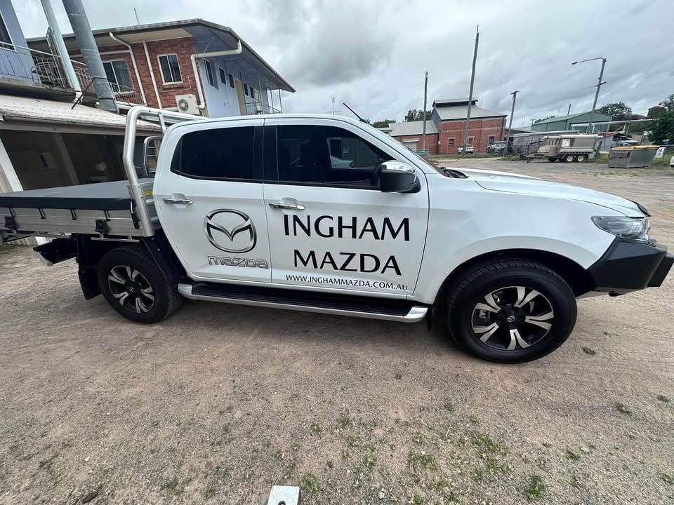 A White Mazda Truck is Parked in a Dirt Lot — Global Signage In Ingham, QLD
