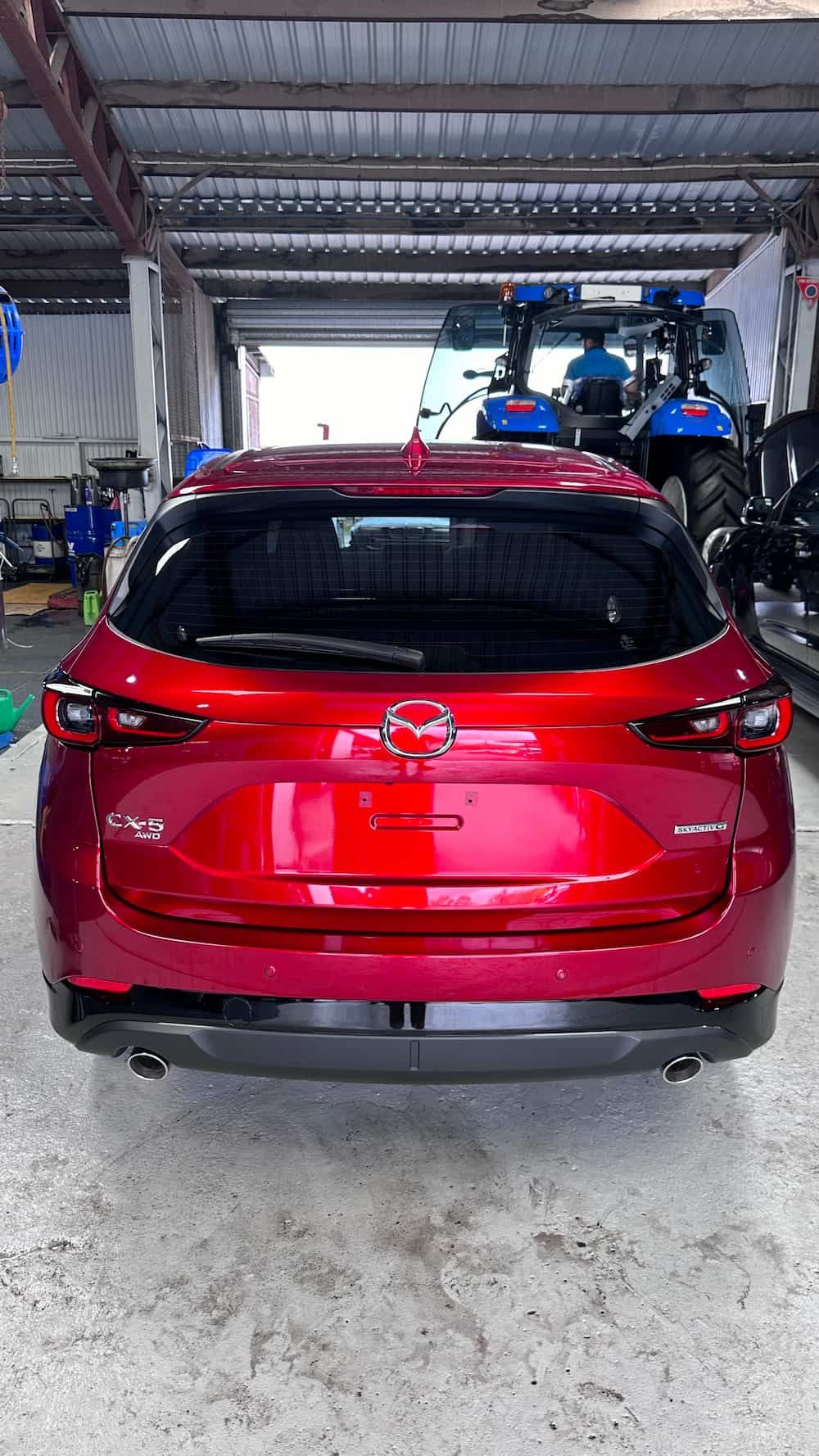 A Red Car is Parked in a Garage Next to a Tractor — Global Signage In Ingham, QLD