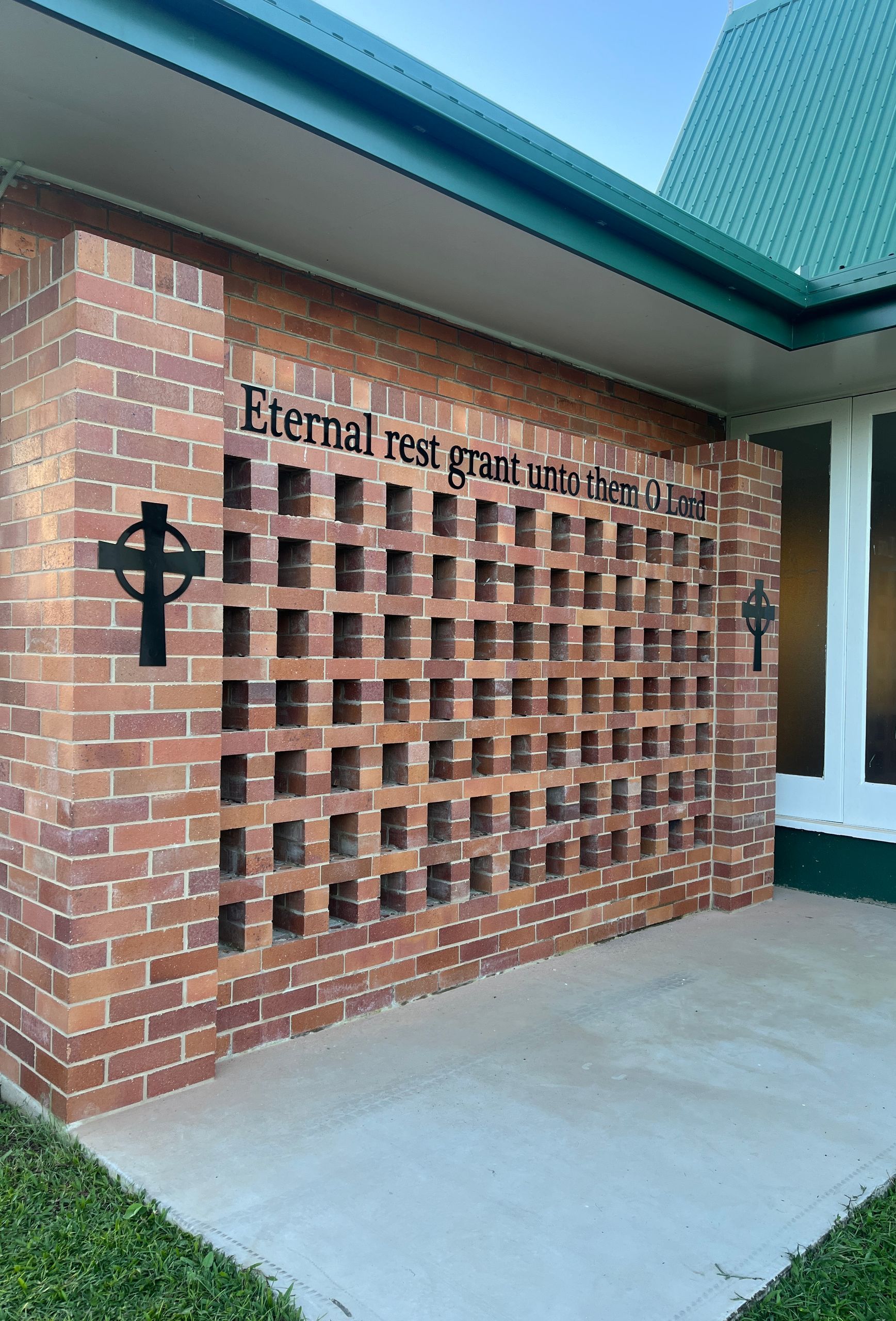 A brick wall with holes in it and a cross on it — Global Signage In Ingham, QLD