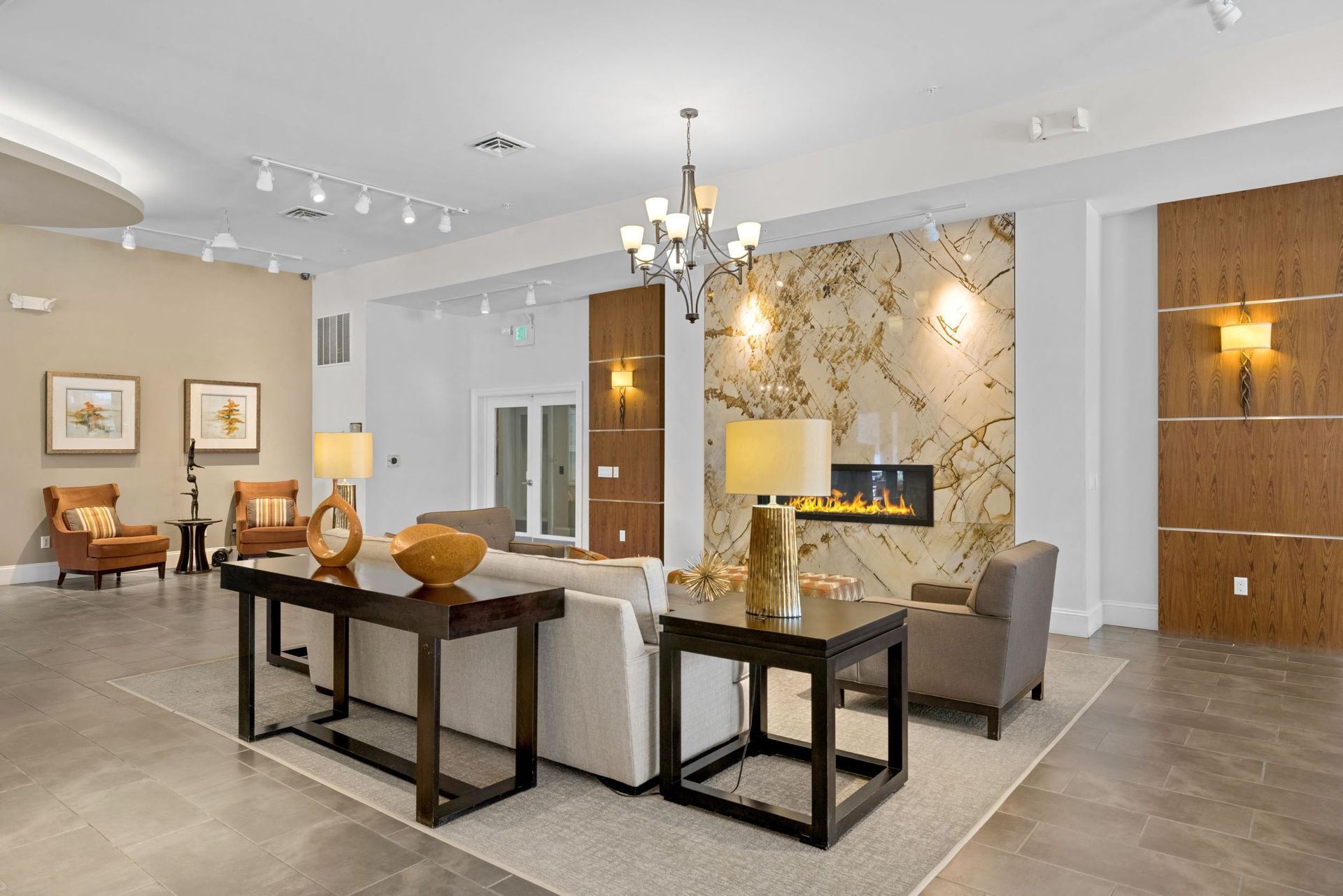 Lobby lounge with beige walls, sofa, armchairs, and a fireplace.
