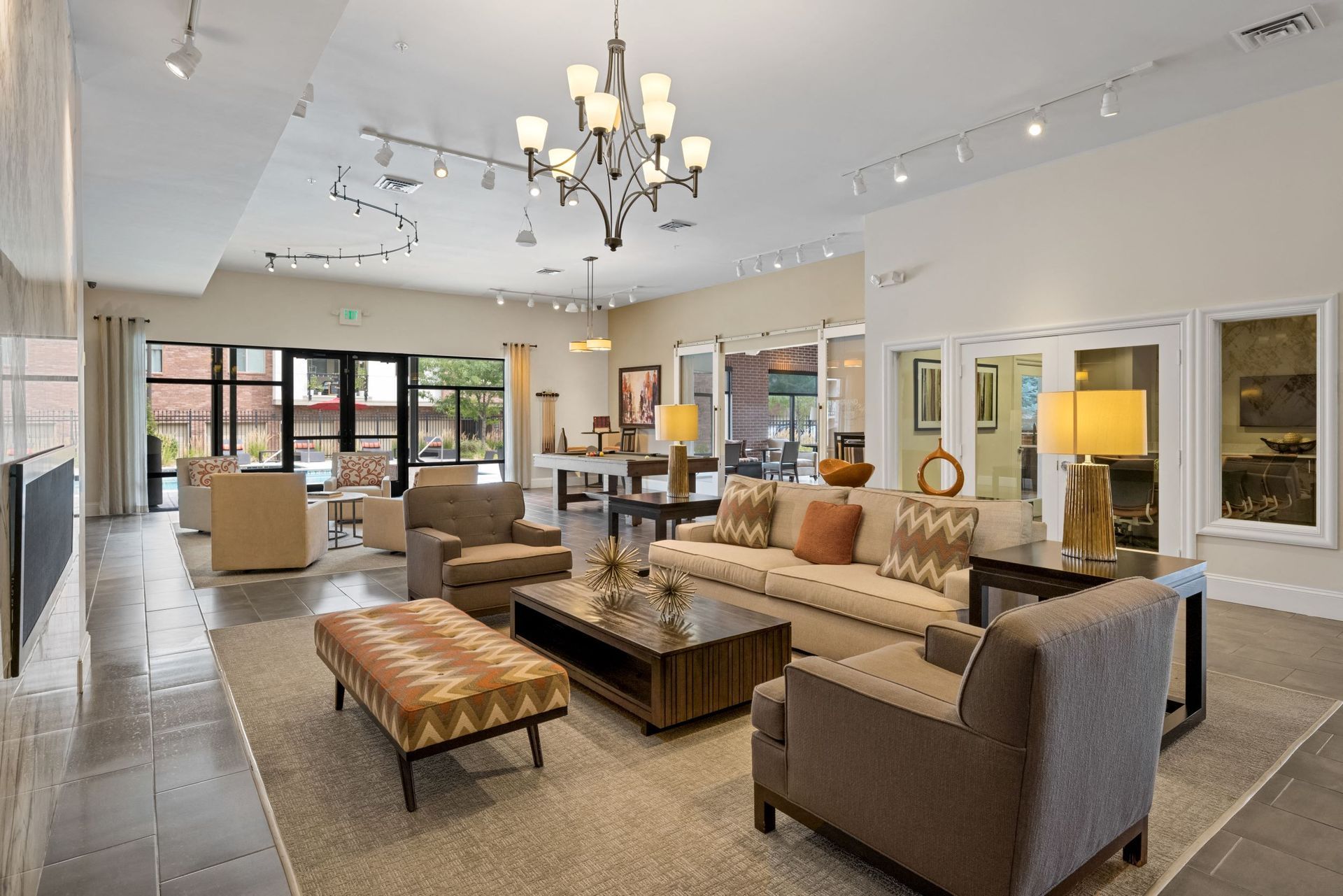 Spacious modern apartment community lounge with beige seating and large windows.