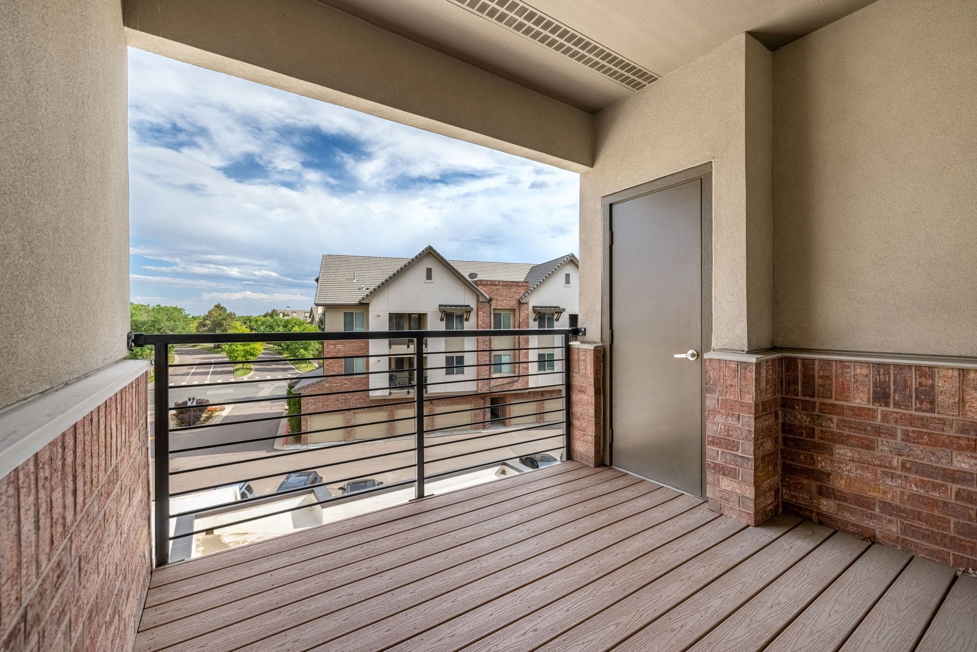 Second-floor balcony with metal railing overlooking neighboring apartment buildings.
