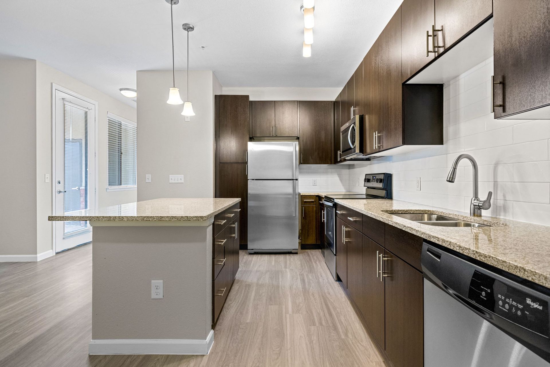 Modern kitchen with granite countertops, dark wood cabinets, stainless steel appliances and an island.