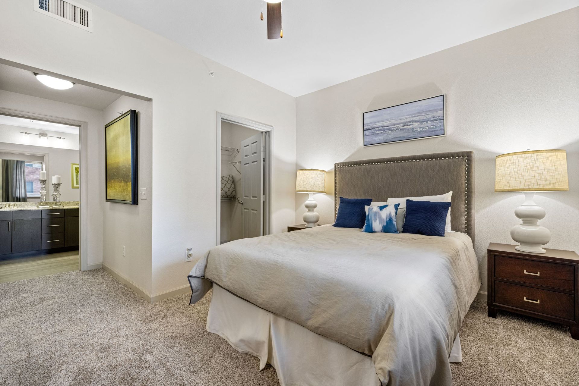 Bedroom with a large bed and tufted headboard, two nightstands with lamps, and a closet nearby.