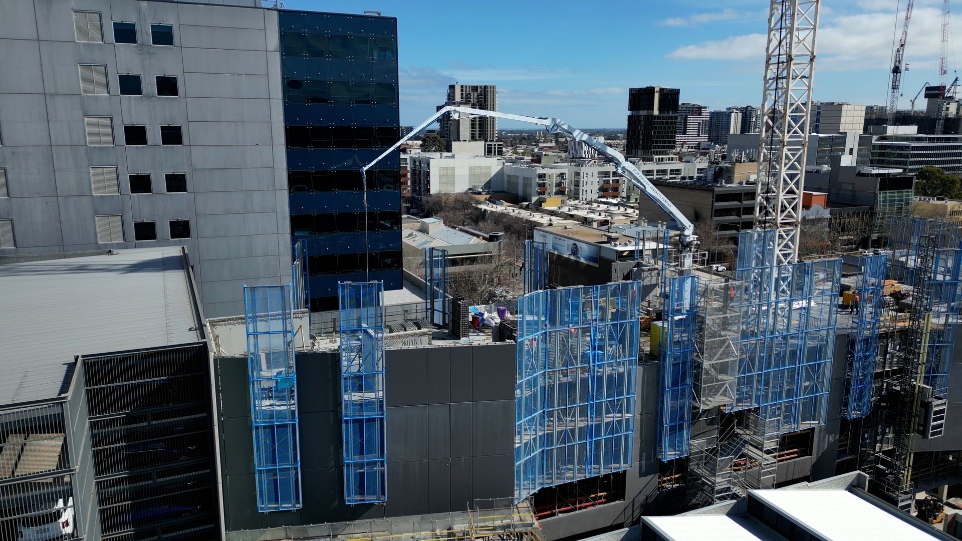 Construction site with tall buildings and a concrete pump reaching for the top.