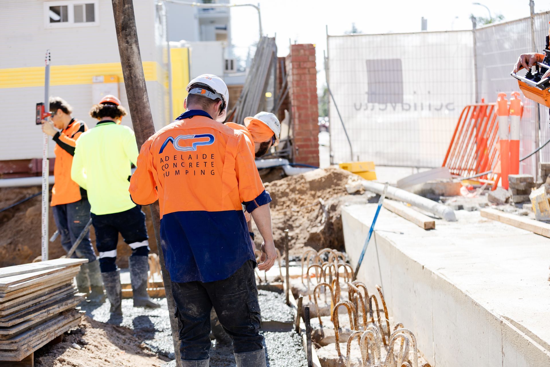 Construction workers in safety vests and hard hats working on a building site.