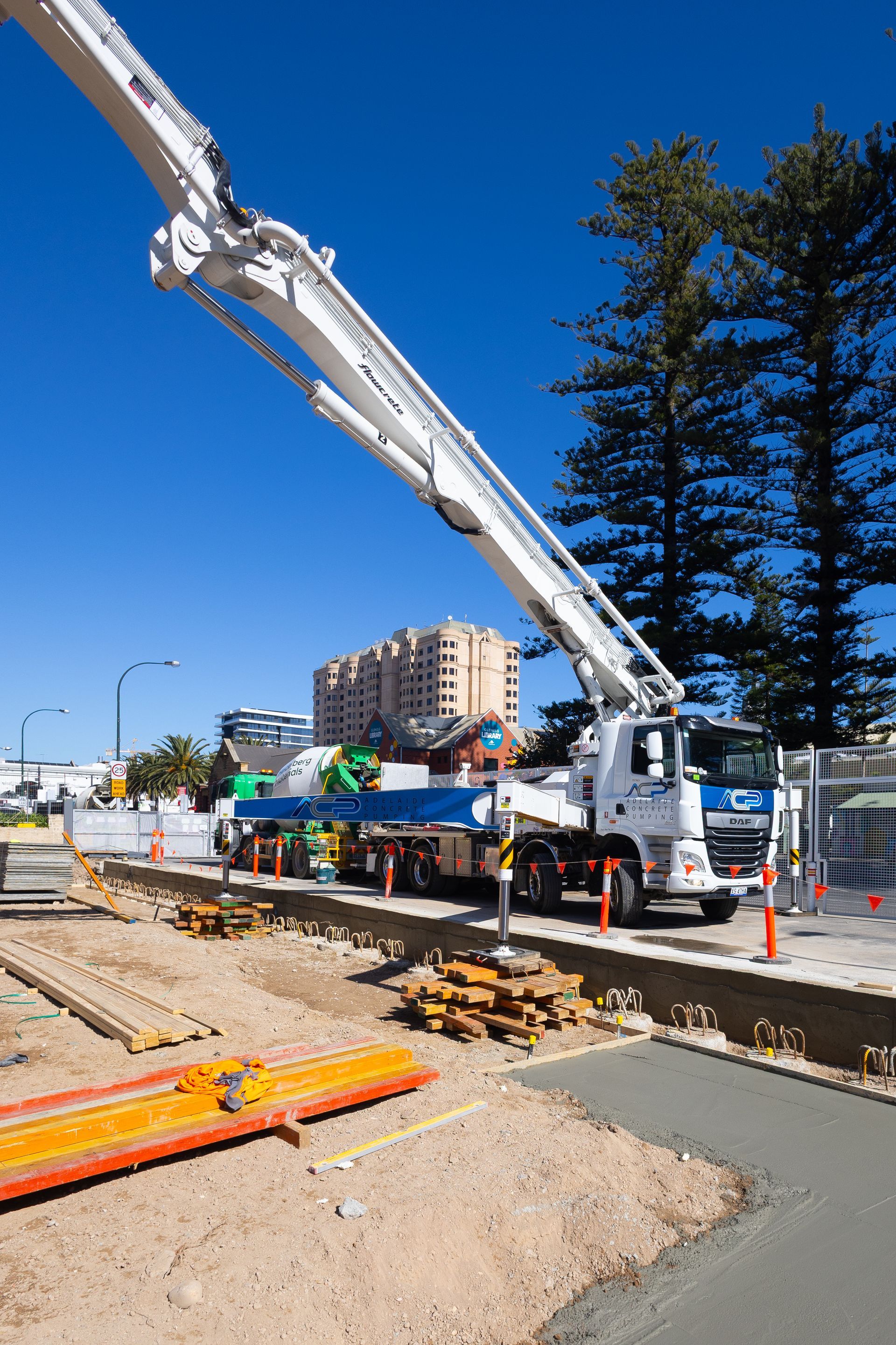Man in work clothes examines a concrete block, black-gloved hands, construction site setting.