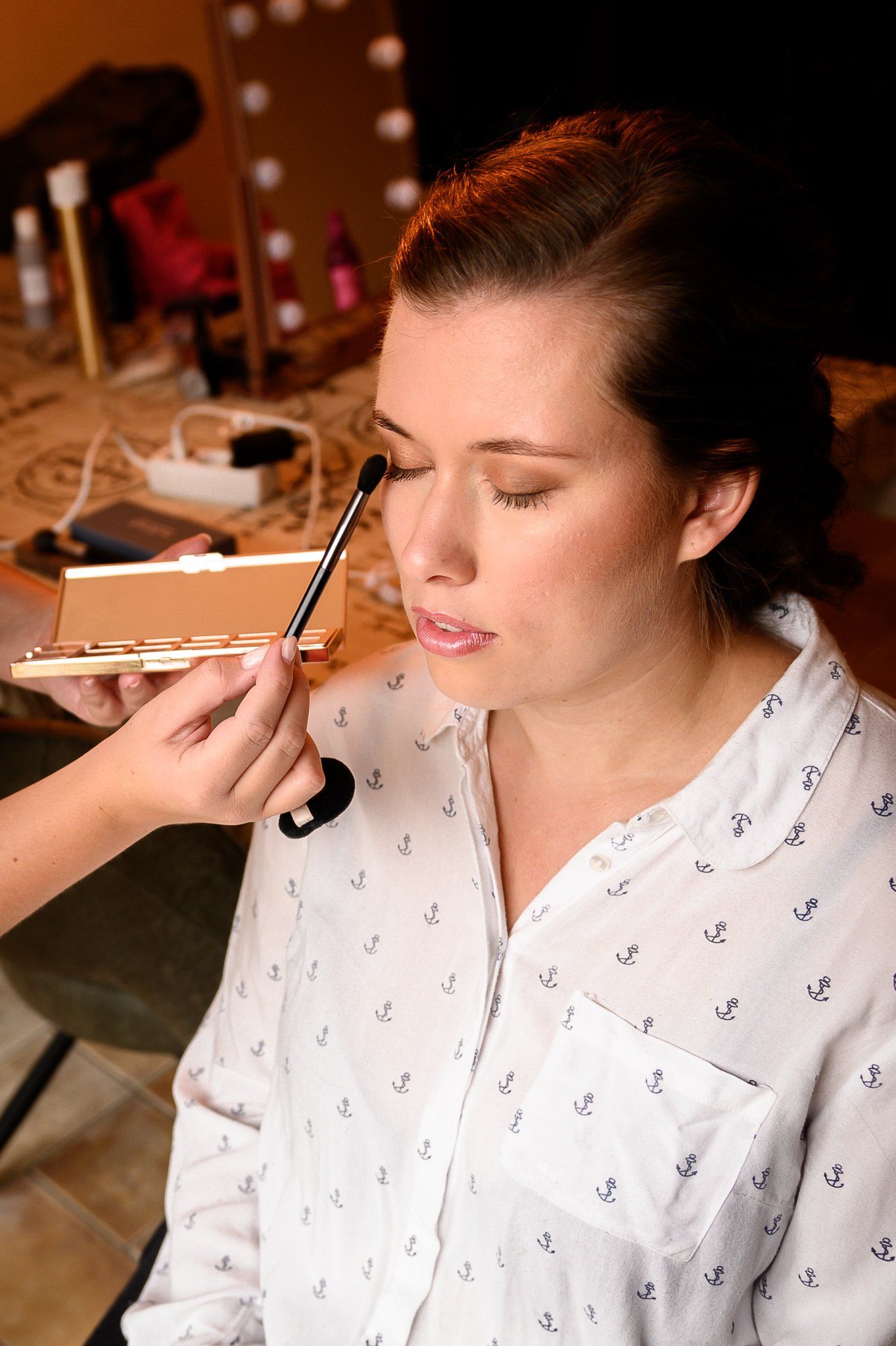 Een bruid krijgt make-up van een visagist.