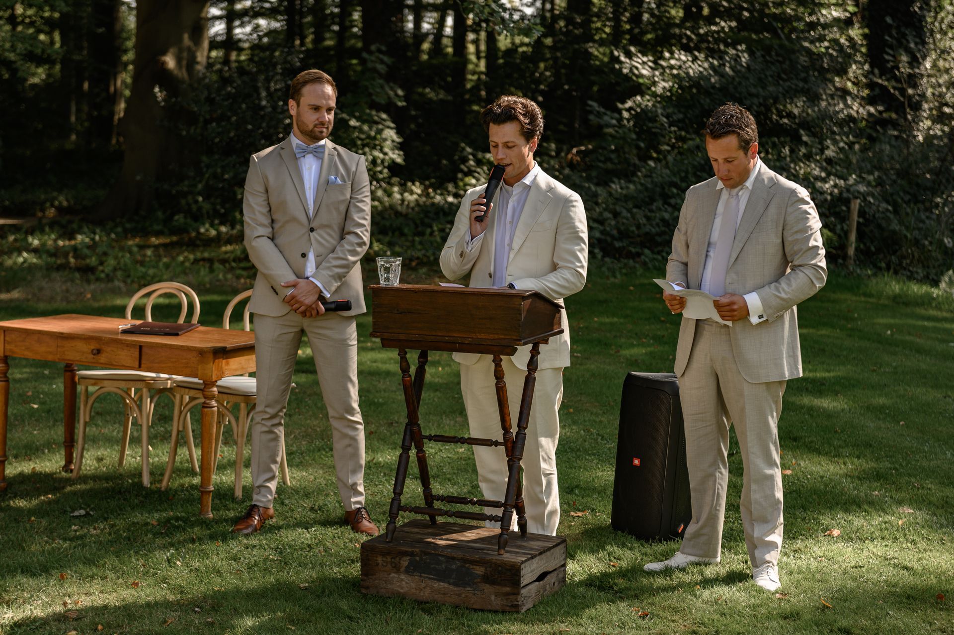 Drie mannen in pak staan voor een podium.